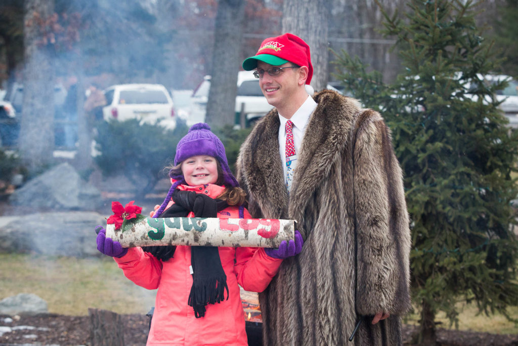 Child holding yule log next to Woodloch event coordinator.