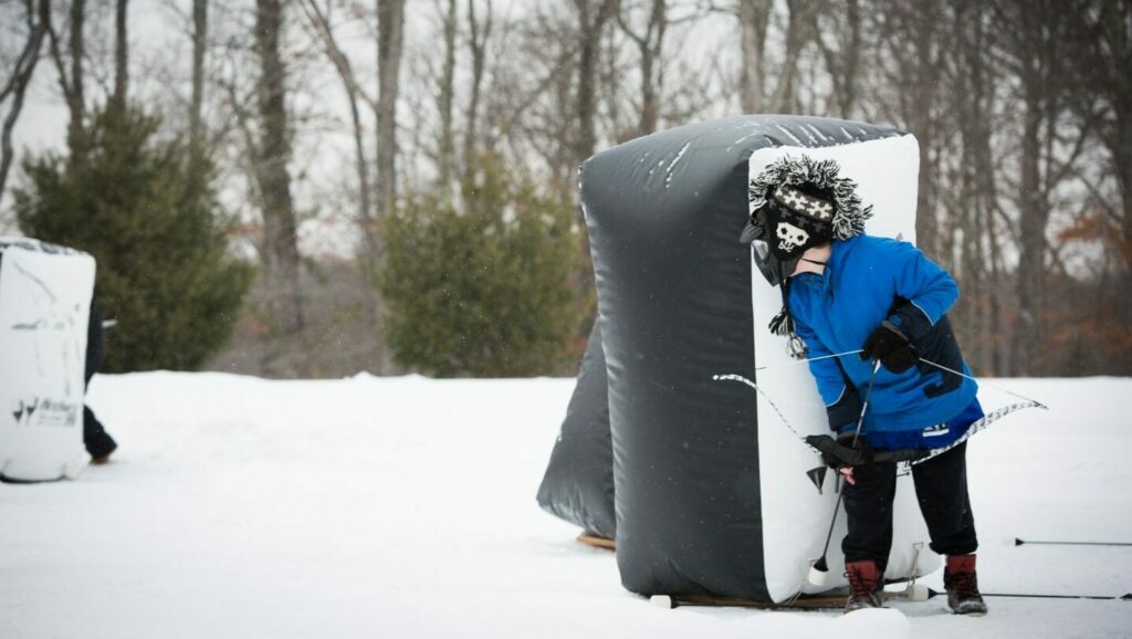 Person with faux bow and arrow behind an inflatable barrier