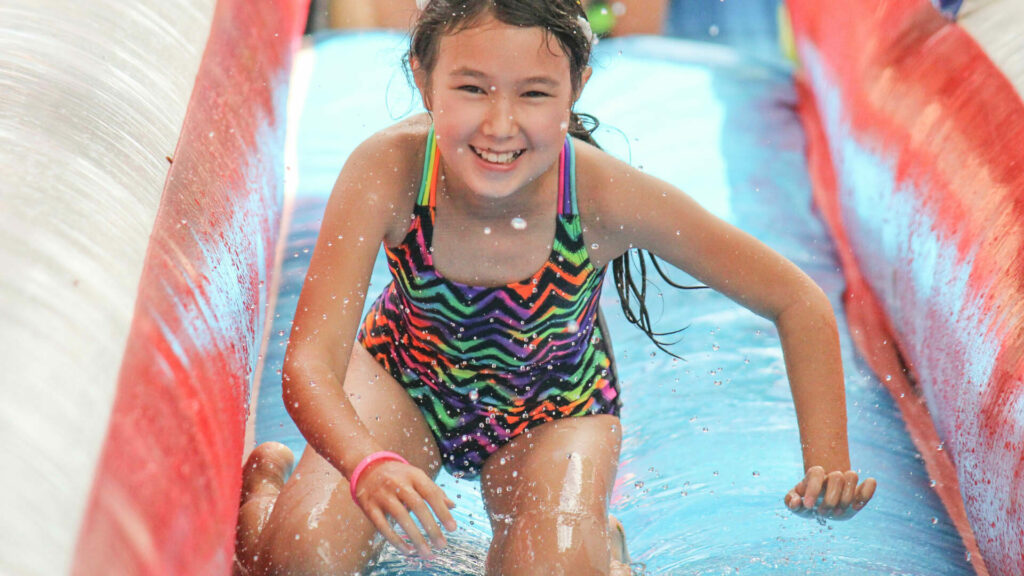 Young girl sliding down an inflatable waterslide.