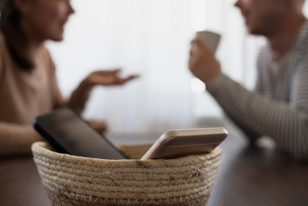 A couple with their phones in a basket on a digital detox retreat in the Poconos.