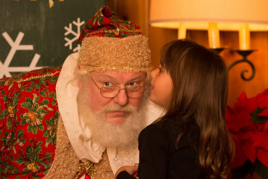 Little girl whispering into Santa's Ear.