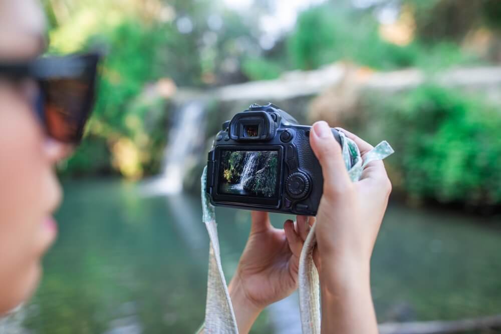 A woman taking photos of a waterfall in the Pocono Mountains.