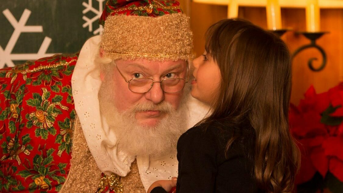 Little girl whispering into Santa's Ear.