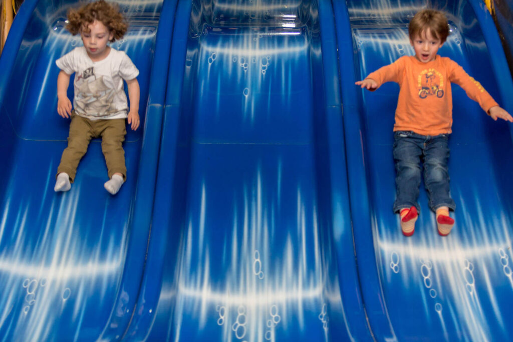 Kids going down the slide at a playground, one of the best things to do indoors at our Poconos resort.