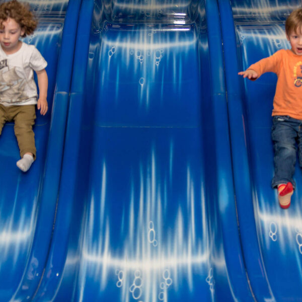 Kids going down the slide at a playground, one of the best things to do indoors at our Poconos resort.