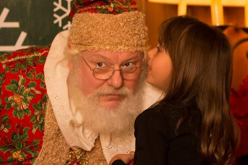 Little girl whispering into Santa's Ear.